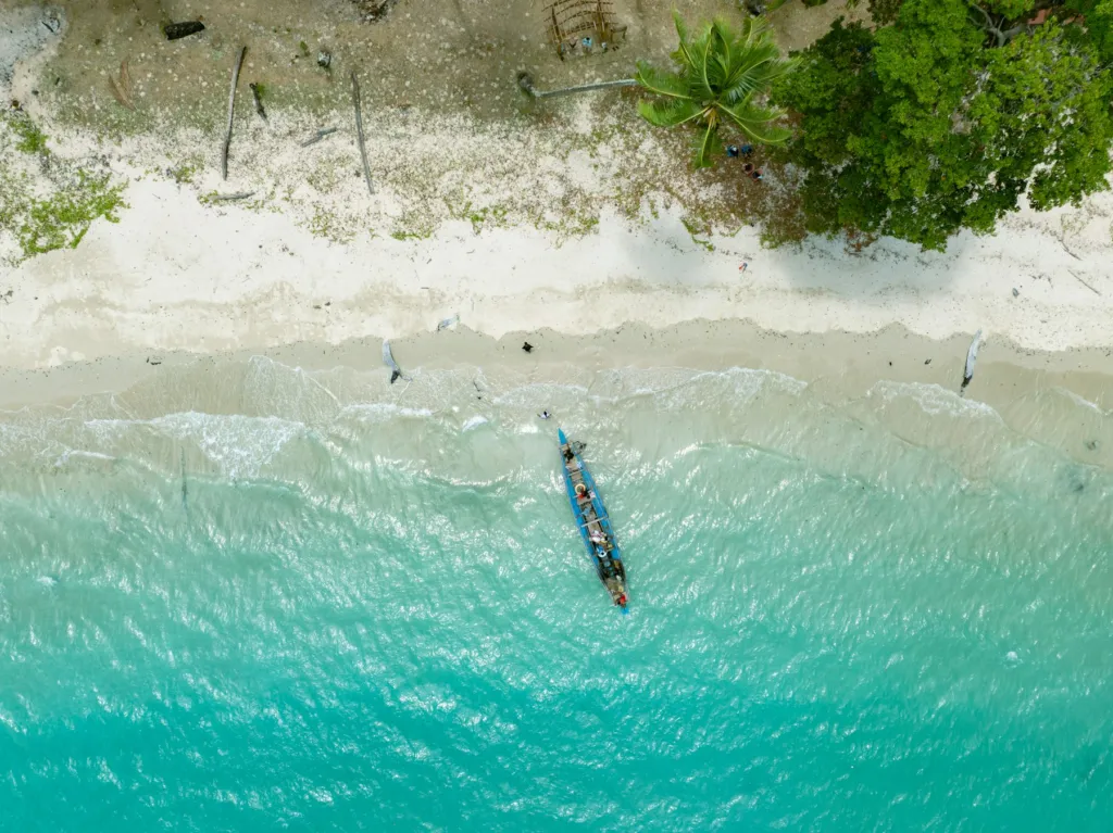 Boat anchored in turquoise water beside a white beach